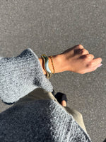 Modelfoto af en Robin guld armbånd. Baggrund er grå. Fra BySofieSønderby
