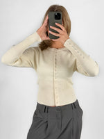 Modelfoto af pige i cremefarvet RORY striktrøje med knapper, samt grå LISA bukser. Alt er fra BySofieSønderby.