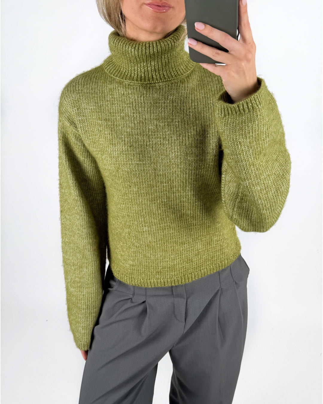 Modelfoto af pige i grøn ROSANNA striktrøje med rullekrave, samt grå LISA bukser. Alt er fra BySofieSønderby.