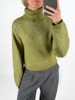 Modelfoto af pige i grøn ROSANNA striktrøje med rullekrave, samt grå LISA bukser. Alt er fra BySofieSønderby.