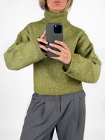 Modelfoto af pige i grøn ROSANNA striktrøje med rullekrave, samt grå LISA bukser. Alt er fra BySofieSønderby.