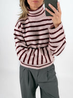 Modelfoto af pige i lyserødstribet ROSANNA striktrøje med rullekrave, samt grå LISA bukser. Alt er fra BySofieSønderby.