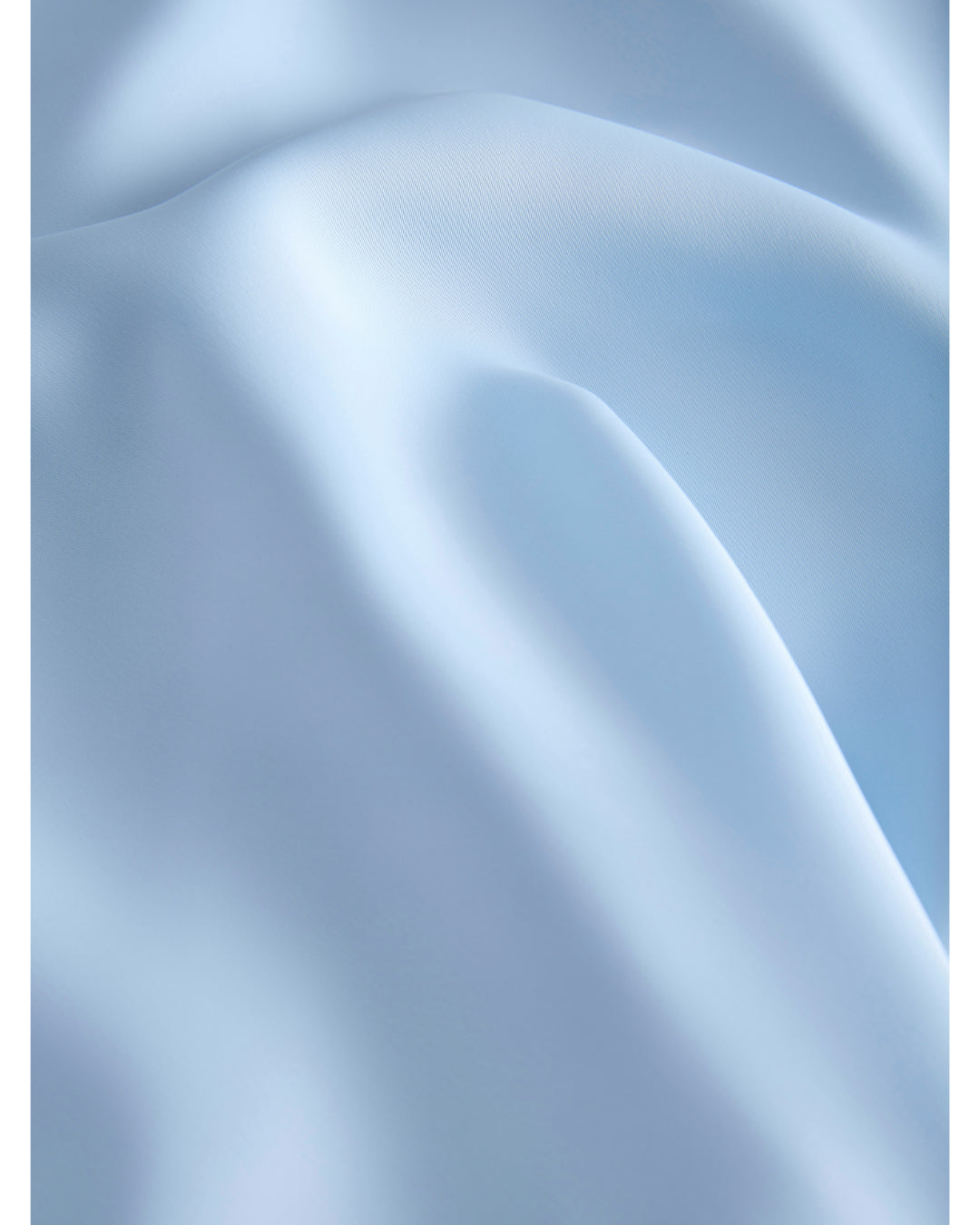 Blått stof, der ligger i bløde folder, skaber en rolig og elegant atmosfære.