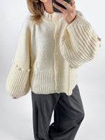 Modelfoto af pige med creme farvet RUTHIE strik cardigan, samt grå MILAN bukser. Set forfra. Alt er fra BySofieSønderby