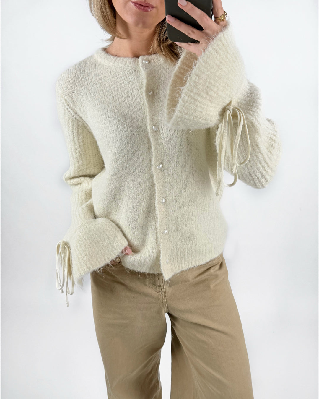 Modelfoto af pige med cremefarvet SALIKA strik cardigan, samt beige TOKYO jeans. Set forfra. Alt er fra BySofieSønderby