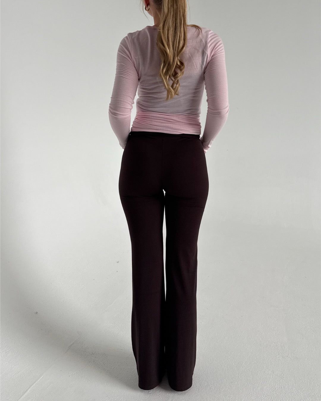 Modelfoto af pige i brune Sania yoga bukser og lyserød Luna wrap bluse. Fra BySofieSønderby