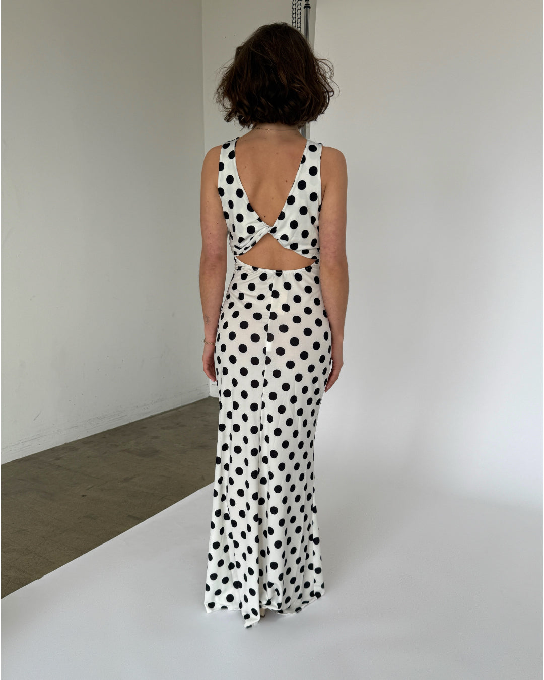 Modelbillede af hvid MAJA kjole med sorte polka prikker. Set bagfra. Fra BySofieSønderby
