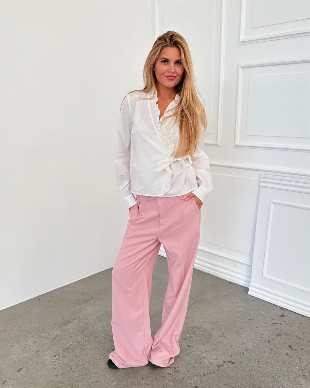 Modelfoto af pige i lyserøde SELENA bukser, samt hvid HOPE top. Alt er fra BySofieSønderby.