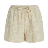 Shorts i blød beige stof, dekoreret med små broderede blomsterhuller, har en elastisk talje og bindebånd, synlig på en hvid baggrund.