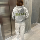 Stemningsbillede af pige der bærer en grå hoodie med army SNDRB tryk og hvide NANNA jeans.  Fra BySofieSønderby
