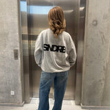 Stemningsbillede af pige der bærer en grå sweatshirt med sort SNDRB tryk og blå NANNA jeans.  Fra BySofieSønderby