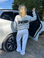 Modelfoto af pige, som bærer SNDRB sweatshirt, grå og NANNA jeans, hvid - alt fra BySofieSønderby