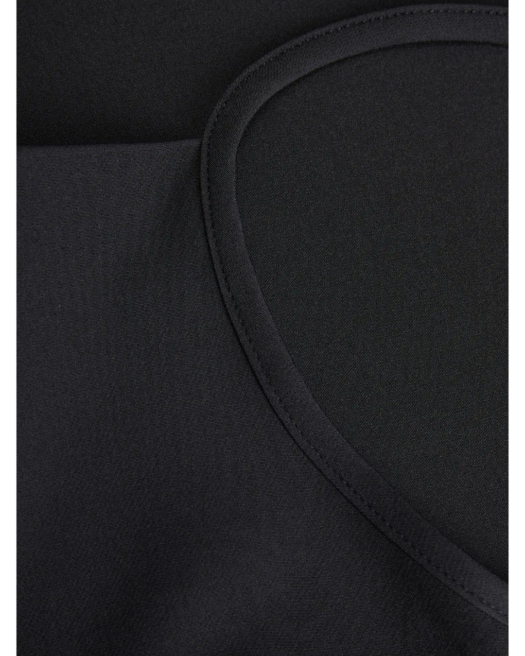 Sort tekstilstof med buet søm, der ligger fladt. Stoffet har en tæt vævning, mens sømmen skaber en let bueformet struktur i en simpel og neutral stil.
