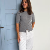 Modelfoto af pige som bærer en Spina cardigan i grå, samt et par hvide Nanna jeans. Alt fra By Sofie Sønderby