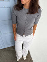 Modelfoto af pige som bærer en Spina cardigan i grå, samt et par hvide Nanna jeans. Alt fra By Sofie Sønderby