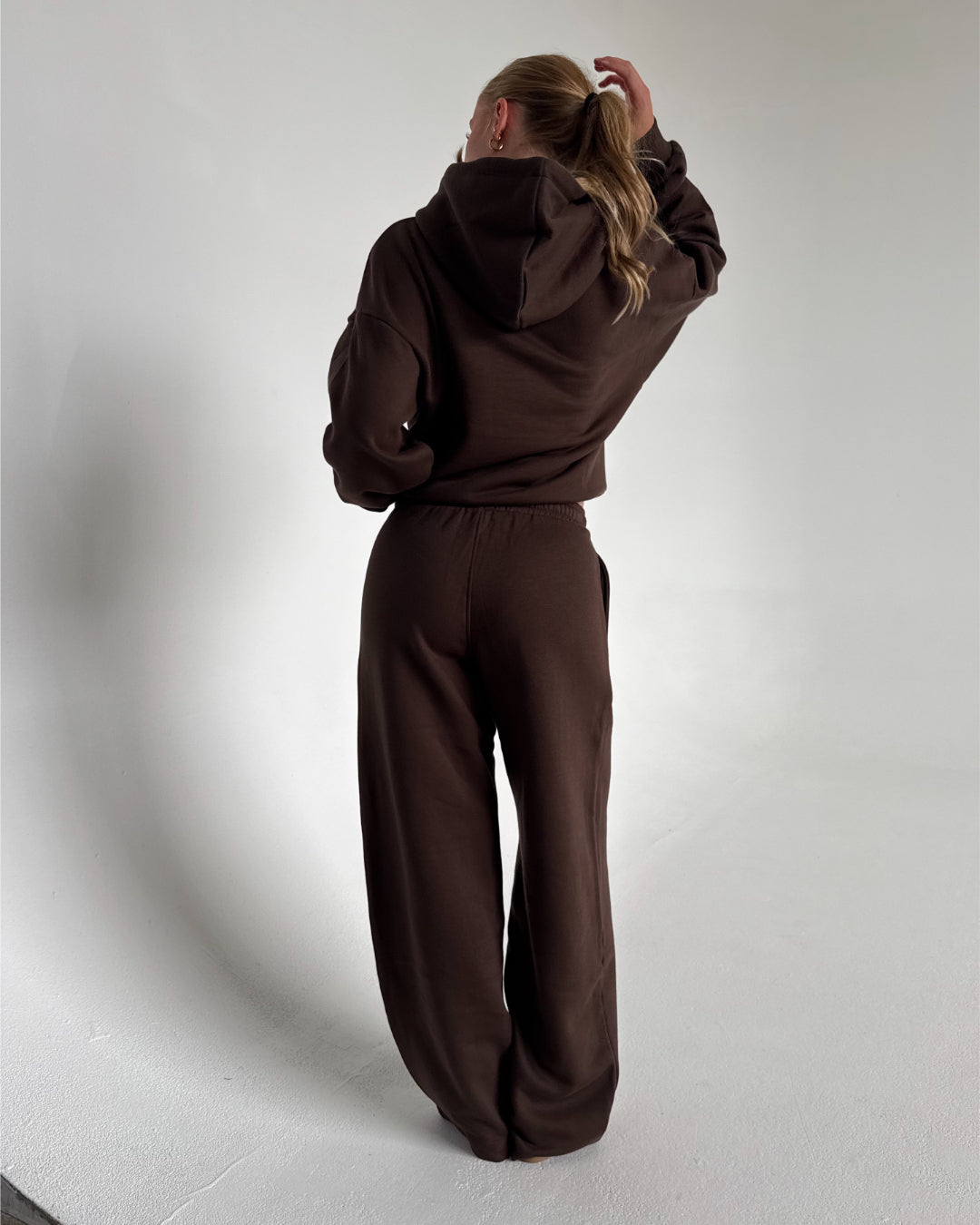 Modelfoto af pige som bærer en Studio Vesterbro bukser i brun, samt Studio Vesterbro hoodie i brun. Alt fra By Sofie Sønderby