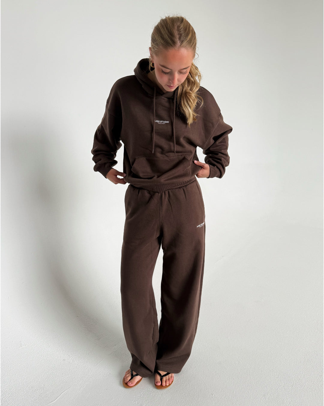 Modelfoto af pige som bærer en Studio Vesterbro bukser i brun, samt Studio Vesterbro hoodie i brun. Alt fra By Sofie Sønderby