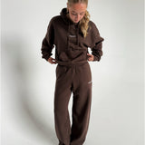 Modelfoto af pige som bærer en Studio Vesterbro bukser i brun, samt Studio Vesterbro hoodie i brun. Alt fra By Sofie Sønderby