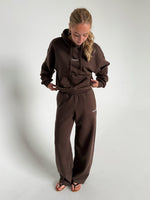 Modelfoto af pige som bærer en Studio Vesterbro bukser i brun, samt Studio Vesterbro hoodie i brun. Alt fra By Sofie Sønderby