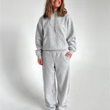 Modelfoto af pige som bærer en Studio Vesterbro bukser i grå, samt Studio Vesterbro hoodie i grå. Alt fra By Sofie Sønderby