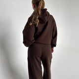 Modelfoto af pige som bærer en Studio Vesterbro hoodie i brun, samt Studio Vesterbro bukser i brun. Alt fra By Sofie Sønderby