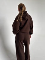 Modelfoto af pige som bærer en Studio Vesterbro hoodie i brun, samt Studio Vesterbro bukser i brun. Alt fra By Sofie Sønderby