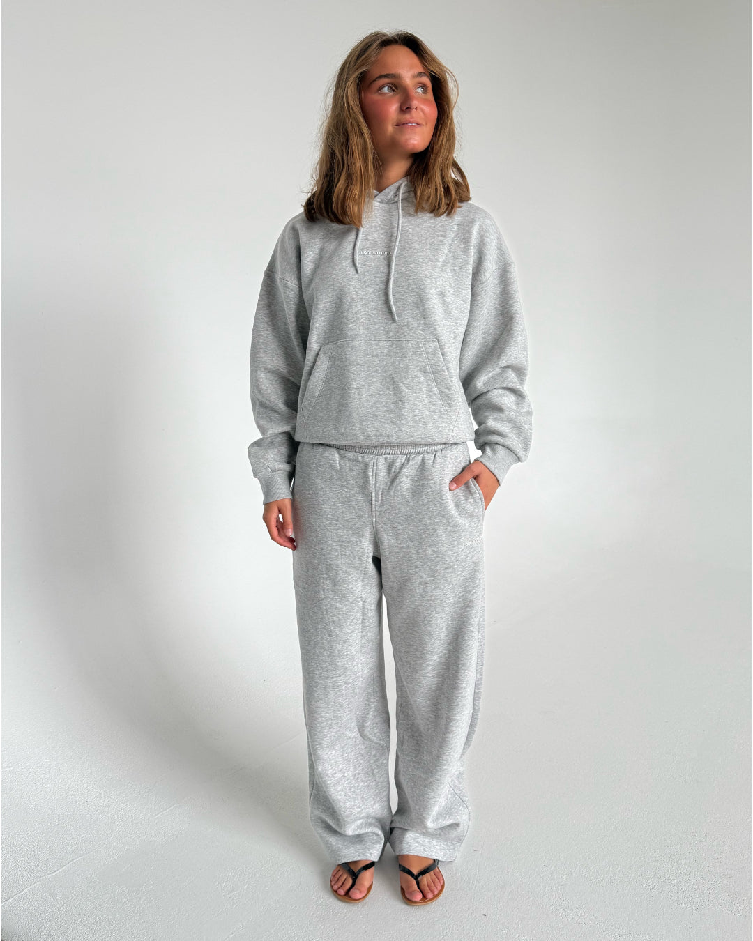 Modelfoto af pige som bærer en Studio Vesterbro hoodie i grå, samt Studio Vesterbro bukser i grå. Alt fra By Sofie Sønderby