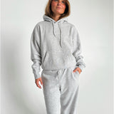 Modelfoto af pige som bærer en Studio Vesterbro hoodie i grå, samt Studio Vesterbro bukser i grå. Alt fra By Sofie Sønderby