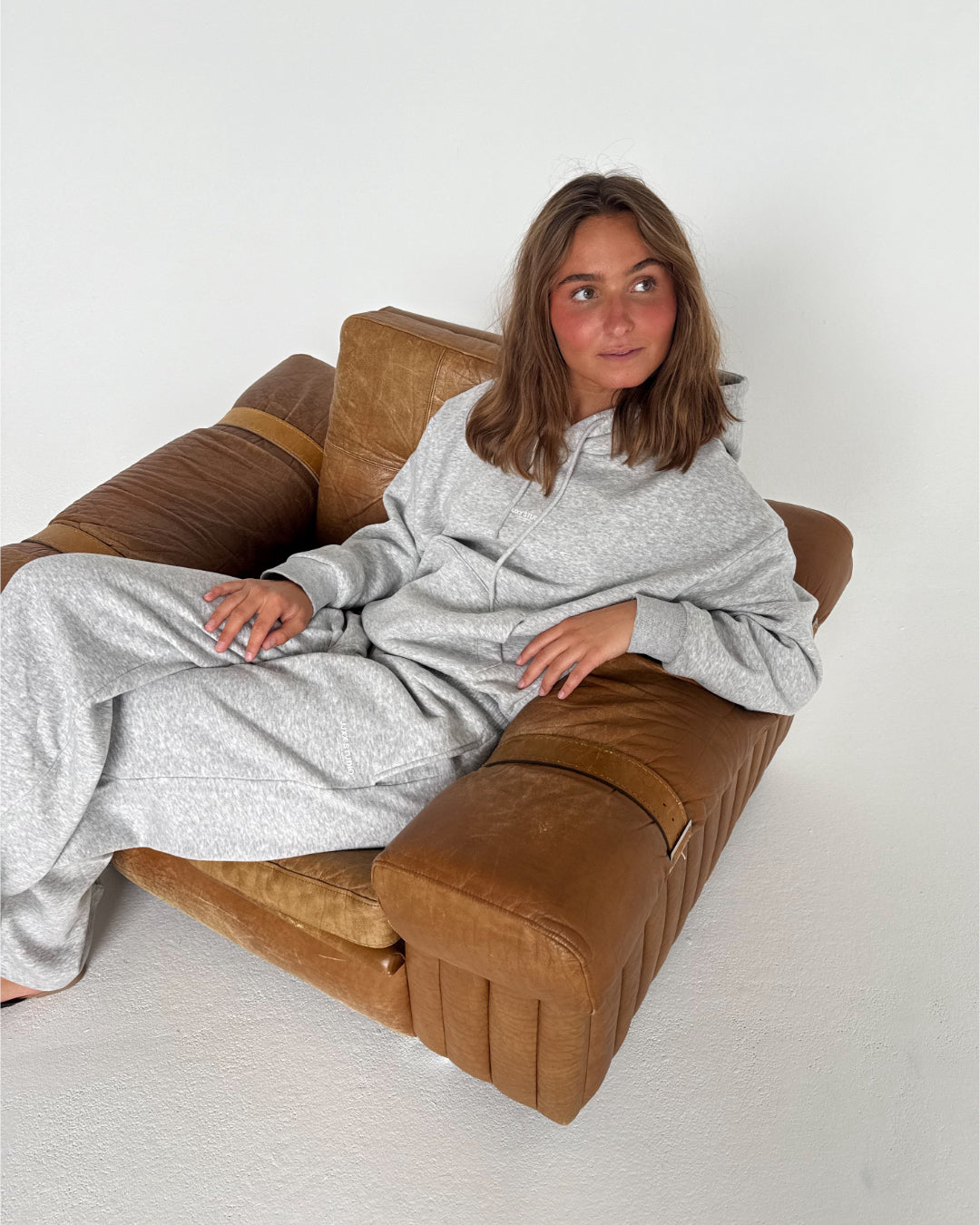 Modelfoto af pige som bærer en Studio Vesterbro hoodie i grå, samt Studio Vesterbro bukser i grå. Alt fra By Sofie Sønderby