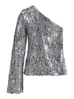 En sølvfarvet pallietbluse med én lang ærme og asymmetrisk one-shoulder design skinner i stærkt lys, sat mod en hvid baggrund.