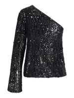 Sort, asymmetrisk bluse prydet med skinnende pailletter; en langærmet side og en skulder fri. Blusen er elegant og velegnet til festlige lejligheder. Baggrunden er hvid.