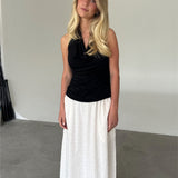 Modelfoto af pige som bærer en sort TAYLOR halterneck top, samt hvid nederdel. Alt er fra BySofieSønderby