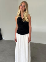 Modelfoto af pige som bærer en sort TAYLOR halterneck top, samt hvid nederdel. Alt er fra BySofieSønderby