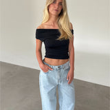 Modelfoto af pige som bærer sort THORA offshoulder top, og lyseblå jeans . Alt er fra BySofieSønderby