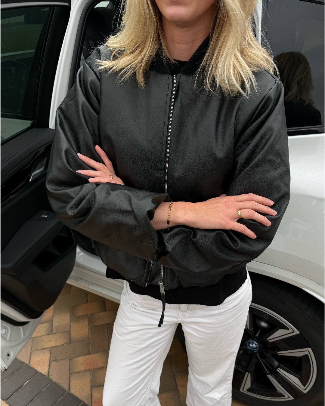 Modelfoto af pige der bærer Trudea jakke i sort udenpå en sort t-shirt, derudover har hun hvide Nanna jeans på. Alt fra BySofieSønderby