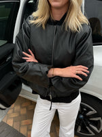 Modelfoto af pige der bærer Trudea jakke i sort udenpå en sort t-shirt, derudover har hun hvide Nanna jeans på. Alt fra BySofieSønderby