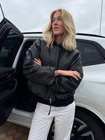 Modelfoto af pige der bærer Trudea jakke i sort, derudover har hun hvide Nanna jeans på. Alt fra BySofieSønderby