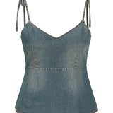 Top i denim med tynde stropper, knyttet øverst, mod en hvid baggrund. Stoffet har et let slidt udseende, og snittet er figursyet med en let svaj i bunden.