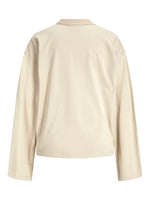 Beige, langærmet T-shirt set bagfra; løs pasform med rund halsudskæring. Enkel, ensfarvet design uden mønster, fotograferet på en ensfarvet baggrund.