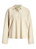 Beige langærmet poloshirt med krave og knaplukning foran. Etiket med teksten "AJXX" inde i nakken. Ingen synlig handling eller særlige omgivelser.