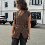 Modelfoto af pige i brun Yui vest med bindebånd, samt grå Nanna jeans. Alt er fra BySofieSønderby