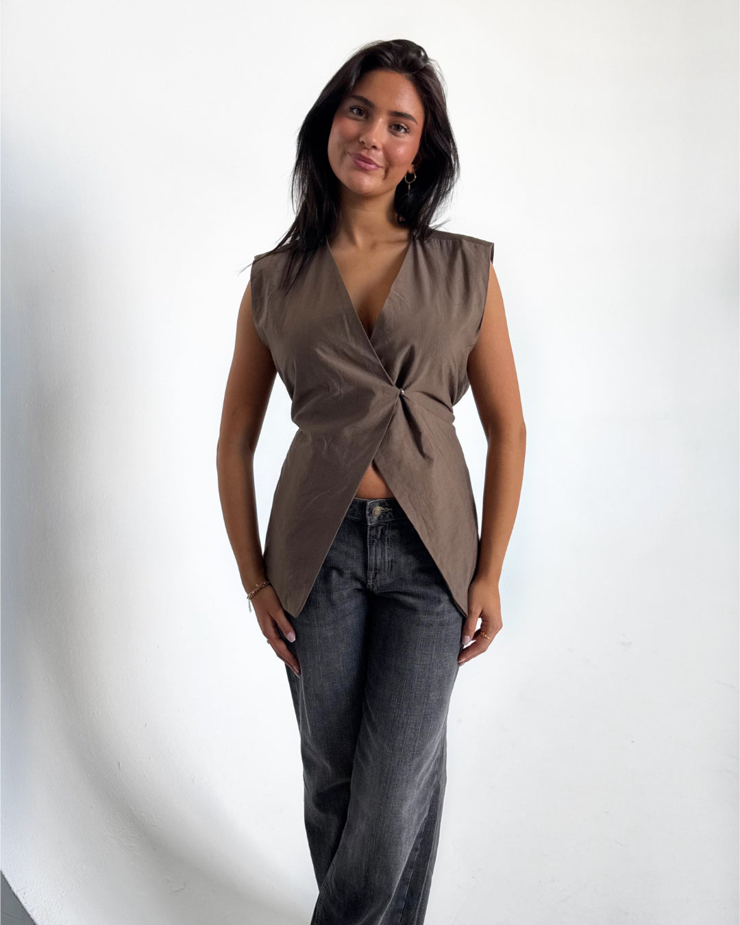 Modelfoto af pige i brun Yui vest med bindebånd, dertil grå Nanna jeans. Alt er fra BySofieSønderby