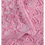 Strikket tekstil i pink med lyse mønstre, ligger udfoldet i lag med en struktureret, blød overflade.