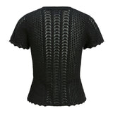 Sort, kortærmet bluse med zigzag-mønster og bølgede kanter, ses fra bagsiden. Stoffet er let gennemsigtigt med forskellige strikmønstre, der skaber tekstur og dybde.