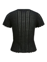Sort, kortærmet bluse med zigzag-mønster og bølgede kanter, ses fra bagsiden. Stoffet er let gennemsigtigt med forskellige strikmønstre, der skaber tekstur og dybde.